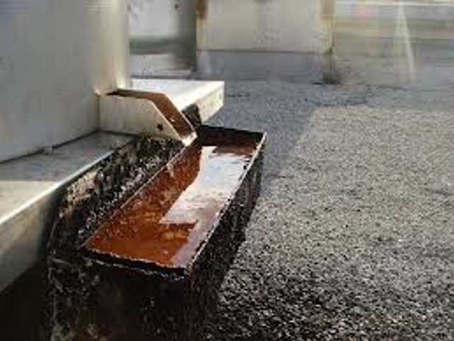Factory rooftop grease box overflowing onto a roof surface