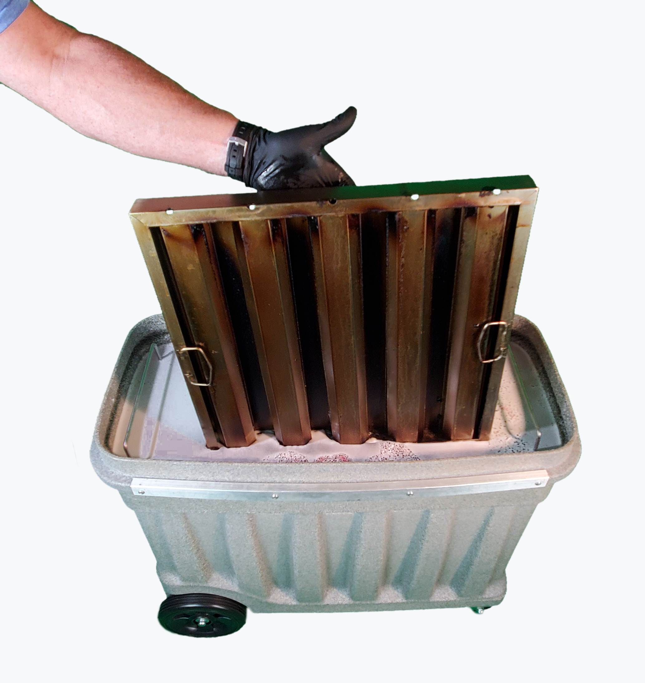 Dirty vent hood filter being placed into a soak tank